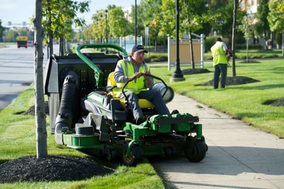 commercial landscape maintenance crew mowing and trimming a retail property